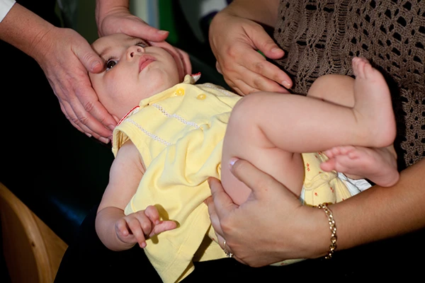 Chiropractic Goleta CA Infant Adjustment An infant in the arms of its mother while being adjusted by a chiropractor