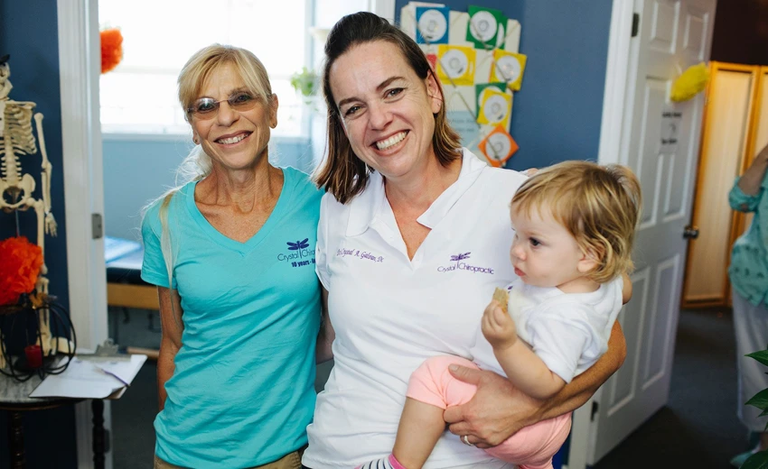 Dr. Crystal Galvan holding a baby and posing with a happy patient